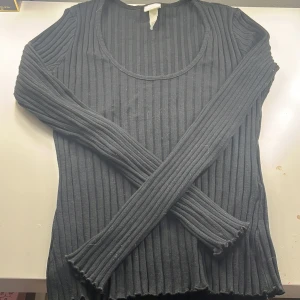 Svart ribbad tröja från H&M - Säljer en svart ribbad tröja från H&M i storlek S. Tröjan har långa ärmar och en rund halsringning. Perfekt för en stilren look. Hör av dig vid intresse! Säljer den för den kommer aldrig till användning 