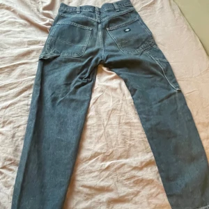 Grå jeansbyxor från Dickies - Säljer ett par blå jeansbyxor från Dickies. Byxorna har en klassisk design med raka ben och praktiska bakfickor. Perfekta för en avslappnad stil.