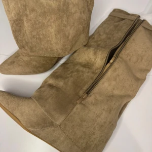 Beige mockastövlar med dragkedja - Snygga beige stövlar i mocka med dragkedja på sidan. De har en spetsig tå och en diskret klack, 7 cm.