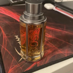 Parfym från Hugo Boss - Säljer en elegant parfym från Hugo Boss med en stilren flaska i glas och metall. Flaskan har en genomskinlig design som visar den gyllene vätskan inuti och har en metallkork. Perfekt för den som vill ha en sofistikerad doft. 50 ml