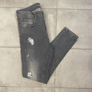 Grå skinny jeans från FSBN - Snygga grå skinny jeans med slitningar. De har en knapp och dragkedja framtill samt klassiska fem fickor. Perfekta för en trendig look.