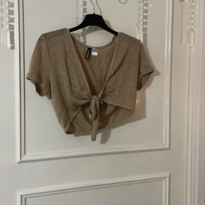 Beige knytblus - Säljer en beige knytblus med korta ärmar och knytning framtill. Perfekt för lager-på-lager. Blusen är använd några gånger men är som ny☺️