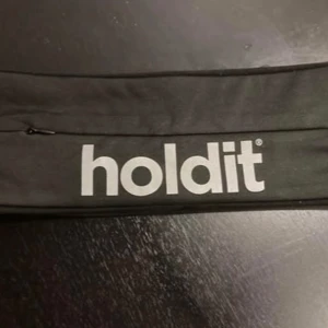 Svart aktivitetsbälte från Holdit - Snyggt svart bälte från Holdit med praktisk ficka och dragkedja. Perfekt för att hålla dina saker säkra under träning eller på språng. Stilren design med Holdit-logga i vitt.