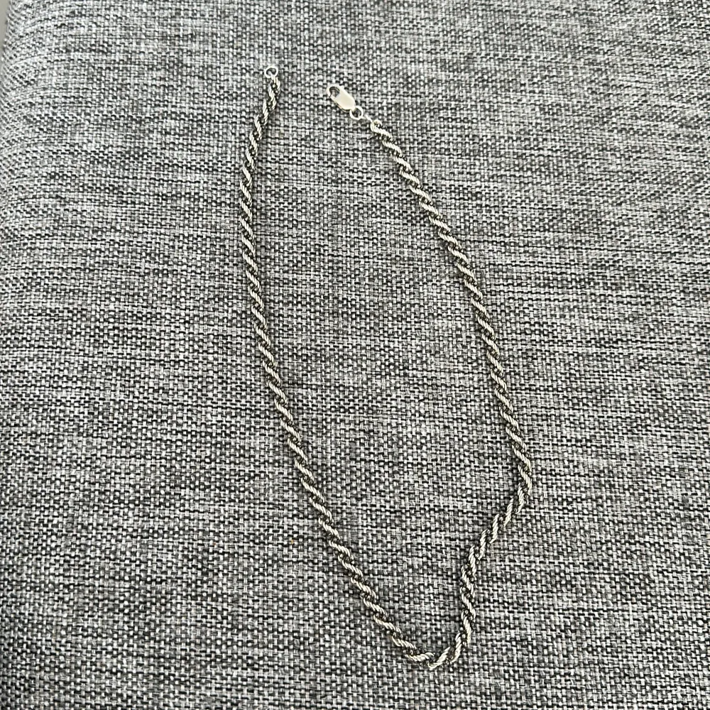 Snyggt silver halsband med en tvinnad design. Perfekt för att ge en stilren touch till din outfit. Halsbandet har ett enkelt lås som gör det lätt att ta på och av stämpel på 925 finns . Asusteet.
