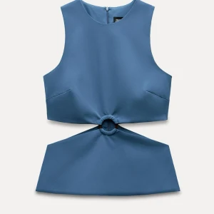 Blå ärmlös topp med detalj - Snygg blå ärmlös topp med unik detalj i midjan. Perfekt för en stilren och modern look. Toppen har en rund halsringning och dragkedja i ryggen.