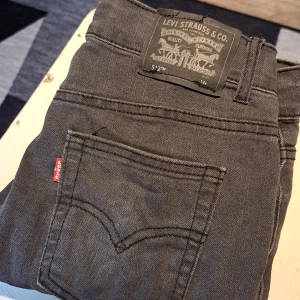 Svart/grå Levi's 512 Slim Taper jeans - Säljer ett par riktigt snygga jeans från levis i bra skick. Jag har haft dem i ett halv år. jag säljer dem för 200kr. Ny pris 450kr. Man kan ha dem om man är 12 13 eller 14 Storlek typ 158. 