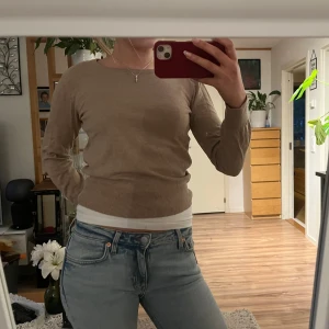 Beige tröja - Säljer en stilren beige tröja med rund halsringning. Tröjan har långa ärmar och en ribbad nederkant som ger en snygg passform. Perfekt för en avslappnad look.