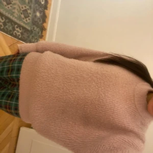 Rosa stickad tröja från Gina Tricot - Mysig rosa stickad tröja från Gina Tricot. Tröjan har en hög krage och långa ärmar, perfekt för kyliga dagar. Den är större i storleken