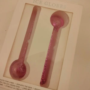 Rosa Ice Globes - Säljer ett par rosa Ice Globes fyllda med glitter. Perfekta för att kyla och fräscha upp huden. De är formade som stavar med en rundad ände för enkel applicering. Använd dem för att minska svullnad och ge ansiktet en uppfriskande känsla. 