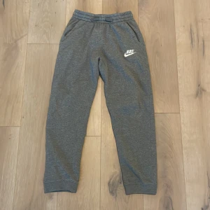 Grå mjukisbyxor från Nike - Säljer ett par grå mjukisbyxor från Nike med elastisk midja och logga på benet. Perfekta för en avslappnad stil. Byxorna har 2 små gröna fläckar på framsidan men syns lite grann. Nypris 400kr 