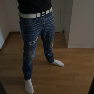 Dsquared2 jeans - Säljer ett par blå Dsquared2 jeans med slitningar. Jeansen har en avslappnad passform och är perfekta för en casual look. Size 46