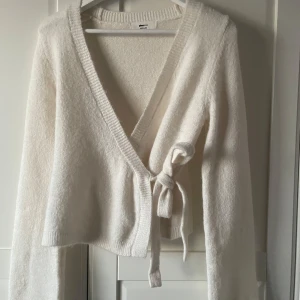 Vit omlottkofta från Gina Tricot - Säljer en mysig vit omlottkofta från Gina tricot. Endast använd en gång så i nytt skick. Köpt för 400kr, skriv för mer frågor eller bilder😊