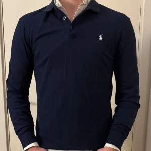 Mörkblå pikétröja från Ralph Lauren - Snygg mörkblå pikétröja från Ralph lauren. Storleken är Medium! Tveka inte på att höra av dig!