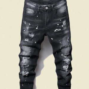 Svarta slitna skinny jeans - Svarta jeans med skinny fit och coola slitningar samt färgstänk för en edgy streetstyle-look. Jeansen har klassisk femficksdesign och är tillverkade i stretchigt denim för extra komfort.