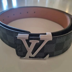 Lv bälte  - Rutigt Lv bälte med silver märke, i nyskick 