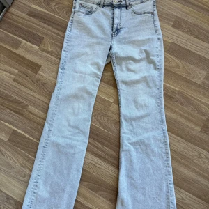 Ljusblå bootcut jeans från H&M Divided - Snygga ljusblå jeans från H&M Divided i bootcut-modell. Klassisk femficksdesign, normalhög/hög midja och raka ben som blir vidare nertill. Jeansen är i mjukt denimtyg och passar perfekt till sneakers eller boots.