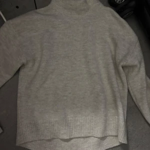 Beige polotröja från Kappahl XS - Mysig beige polotröja från Kappahl i storlek XS. Tröjan är stickad med ribbade muddar och har en hög polokrage som ger en chill och stilren vibe. Perfekt för lager-på-lager och passar till allt från jeans till kjol.
