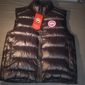 Svart dunväst från Canada Goose - KAN DISKUTERA PRIS VID SNABB KÖP. om du ser detta efter 9de är jag i semester så passa på! Säljer en svart dunväst från Canada Goose med klassisk logga på bröstet. håller dig varm med stil. Passar dig som är 165-175cm 5'5-5'7