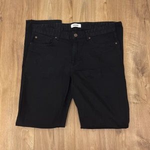 Svarta jeans från Kappahl - Svarta jeans från Kappahl med klassisk femficksdesign och knappgylf. Byxorna har en rak passform och är tillverkade i ett mjukt bomullsmaterial med lite stretch. Perfekta för en clean och stilren look.