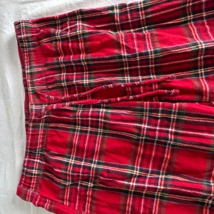 Röda rutiga pyjamasbyxor  - Säljer ett par röda pyjamasbyxormed klassiskt rutigt mönster och snörning i midjan. Perfekta för chill dagar hemma eller när du vill ha det extra bekvämt. Mjukt material och avslappnad passform.