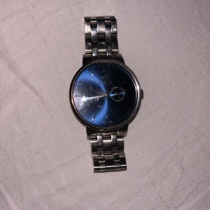 Blå och silverfärgad klocka från GANT - Stilren klocka från GANT med blå urtavla och silverfärgat armband i metall. Urtavlan har minimalistiska markeringar och en extra liten visare för sekunder. Länkat armband med klassisk låsning och GANT-logga på spännet. Perfekt accessoar för en clean look. Ny pris 2399kr
