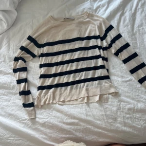 Randig beige och svart tröja - Snygg beige tröja med svarta horisontella ränder och rund hals. Långärmad och i tunnare, mjukt material som känns skönt mot huden. Perfekt för lager-på-lager och enkel att styla till jeans eller kjol.