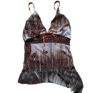 Vintage Brun paisleymönstrad linnetopp - Söt volang asymmetrisk topp med paljett/rhinestones. Strl L men mer en S-M i size. Enda defekt är på de orangea bandet på framsidan har svarta prickar på sig. Kan eventuellt klippa bort bandet. Annars ej så märkvärdigt. 