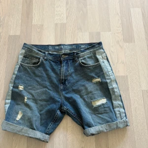 Loose fit jeansshorts Shine Original - Snygga blå jeansshorts från Shine Original i loose fit-modell. De har slitna detaljer, upprullade benslut och klassiska fem fickor. Shortsen har en ljusare rand längs sidorna som ger en cool kontrast. Perfekta för en avslappnad stil under sommaren. Knappt använda 
