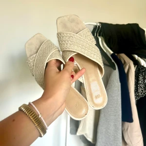 Beige sandaler med blockklack från H&M - Snygga beige sandaler från H&M med breda korslagda band i vävt tyg och fyrkantig tå.
