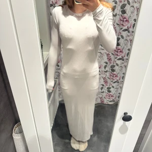 Vit ribbad långklänning 157 XS - Långklänning i mjukt ribbat tyg från Lager 157 i en ljus beige/vit ton. Klänningen har långa ärmar och en enkel, rak passform som känns både chill och stilren. Perfekt för dig som gillar minimalistisk och clean stil. Klänningen är ny utan prislapp