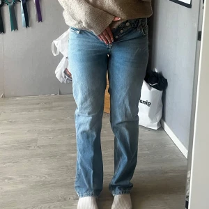 Ljusblå raka jeans från 157 Icon - Trendiga jeans med låg midja som framhäver figuren på ett snyggt och modernt sätt. Den raka passformen ger en klassisk silhuett som passar till alla tillfällen, både till vardags och till fest! Jeansen har praktiska fickor både fram och bak. Knappgylf framtill och bälteshällor i midjan gör det enkelt att komplettera med ditt favoritbälte för en personlig touch. Ett måste i garderoben för dig som älskar stilren denim!