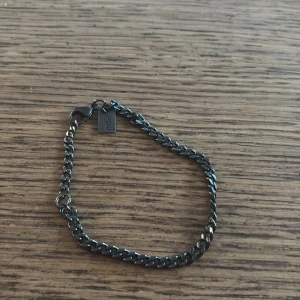 Svart kedjearmband  - Stilrent svart armband med en liten bricka vid låset. Man kan göra så den blir mindre eller större! 