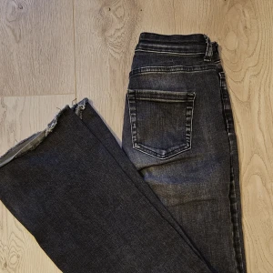 Mörkgrå jeans från ONLY med slits - Snygga mörkgrå jeans från ONLY med fransad kant nertill. Lågmidjade, bootcut jeans med slits nertill. Storlek 32