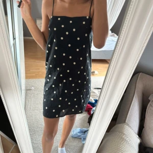 Svart prickig linneklänning H&M - Svart kort klänning från H&M i linneblandning med vita prickar. Den har tunna axelband och rak passform. I storlek 36/S och endast använd fåtal gånger! 