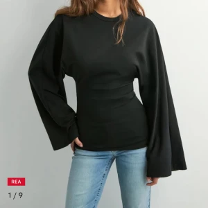 Svart långärmad topp med vida ärmar - Snygg svart långärmad topp med riktigt vida ärmar och figurnära passform i midjan. Enkel design med rund halsringning, perfekt för dig som gillar stilrena plagg med en twist. Materialet känns mjukt och stretchigt, vilket gör den bekväm att bära hela dagen. (OANVÄND!)
