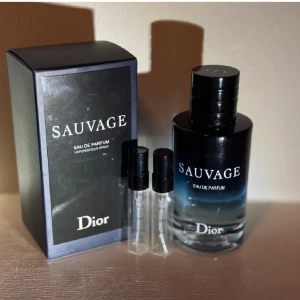 Dior Sauvage Eau de Parfum - Dior Sauvage Eau de Parfum med elegant svart och blå glasflaska, stilren svart kartong och två små provflaskor. Doften är maskulin och modern, perfekt för dig som gillar fräscha och kryddiga toner. Flaskan har en lyxig känsla och tydlig Dior-logga.