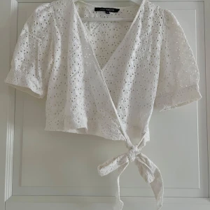 Vit omlottopp - Superfin vit omlottopp från KappAhl i storlek XS., puffiga korta ärmar och knyt i midjan. Knappt använd med fina mönster