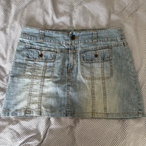 Vintage jeanskjol ljusblå - Ljusblå jeanskjol från Vero Moda med två fickor framtill och snygga sömdetaljer. Knäppning med knapp och dragkedja. Inga bilder på men måtten är: midja tvärs över: 40cm. Längd: 32,5cm🦋🦋🦋