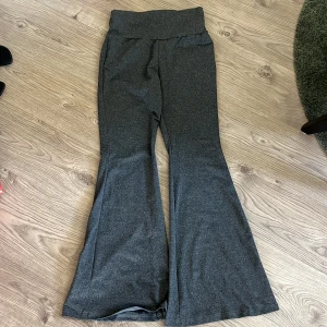 Grå bootcut byxor med hög midja - Snygga grå byxor med bootcut-ben och hög midja. Mjukt och stretchigt material som sitter skönt och ger en clean look. Perfekta för dig som gillar en trendig och bekväm stil.