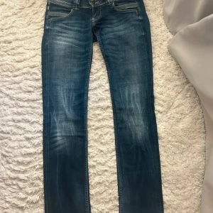 Låg midjade jeans med raka ben - Snygga blå jeans med låg midja och raka ben. Jeansen har klassisk femficksdesign, slitningar framtill och cool broderad bakficka. Säljer för att dom tyvär inte passar mig men dom är i väldigt bra skick