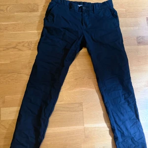 Svarta chinos från Reserved slim fit - Snygga svarta chinos från Reserved i slim fit-modell. Byxorna har klassisk design med fickor i sidorna och bälteshällor. Perfekta för dig som gillar en stilren och enkel look. Materialet känns mjukt och bekvämt.