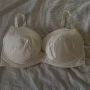 Vit satin bh från PXC Underwear 75E - Helt ny.    Snygg vit bh från PXC Underwear i glansigt satinliknande material. Axelbandslös design med vadderade kupor och mjuk insida för extra komfort 