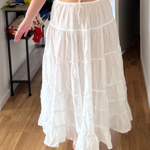 Vit volangkjol  - Superfin lång vit kjol med volanger och resår i midjan. Kjolen har en luftig och flowy känsla, perfekt för varma dagar. Storlek M men har knytband i midjan för extra passform. Funkar för S,M och L. Helt ny aldrig! Köpt på asos. Frakt tillkommer 