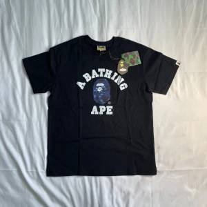 Bape T-shirt Svart - 🔥 Säljer en snygg BAPE (A Bathing Ape) T-shirt 👕 i svart med blå kamouflage-logga 💙🦍. Helt ny, aldrig använd och med tag kvar 🏷️. Riktigt fin passform och skön bomull 🔥 Perfekt för dig som gillar streetwear med stil 😎✨ ✅ Ny ✅ Oanvänd ✅ Snabb leverans 📦 📩 Skicka gärna meddelande vid frågor! Först till kvarn 💥👟 