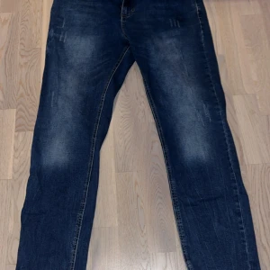 Mörkblå jeans med raka ben - Säljer ett par mörkblå jeans med snygga slitningar och raka ben. Jeansen har klassisk femficksdesign och är tillverkade i robust denim. Perfekta för dig som gillar en enkel och tidlös look. Mina favorit jeans som tyvärr inte längre passar mig