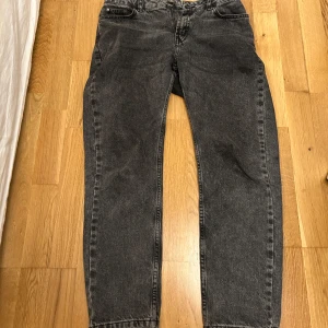 Grå loose fit jeans från Grunt - Säljer ett par mörkgrå jeans från Grunt i modellen Street Loose. De har en loose fit med raka ben och klassisk femficksdesign. Jeansen är tillverkade i bomull och har en snygg tvättad look som passar perfekt till en avslappnad stil.