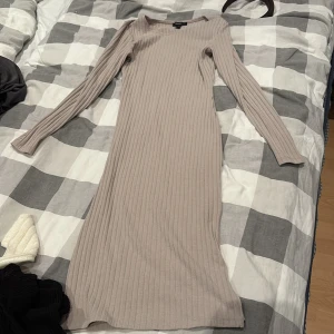 Beige ribbad långklänning Forever 21 - Säljer en beige ribbad långklänning från Forever 21. Klänningen har lång ärm, rund halsringning och är figurnära i modellen. Perfekt för dig som gillar en enkel men stilren look. Materialet är mjukt och stretchigt för extra komfort.