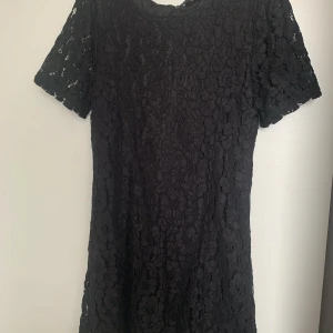 Svart spetsklänning från Bik Bok - Supersnygg svart kortklänning från Bik Bok i spets med korta ärmar och dragkedja bak. Klänningen har en figurnära passform och är helfodrad under spetsen. Perfekt för dig som vill ha en stilren och trendig look.