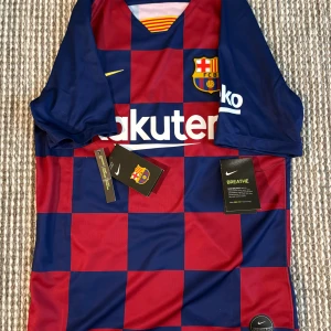 FC Barcelona Fotbollströja 19-20 - Hej! Jag säljer denna FC Barcelona hemma ställ från säsongen 2019-2020  från Nike i blått och rött rutigt mönster. Det är ingen spelares namn på baksidan av tröjan. Tröjan storlek är herr S, vid nån minsta fundering av tröjan är den bara att höra av sig. Priset kan sänkas vid en snabb affär💨