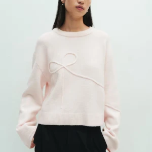 Ljusrosa stickad tröja med rosettdetalj - Superfin ljusrosa stickad tröja, litet hål på tröjan som ja tänker kanske går att laga men annars i fint skick💞